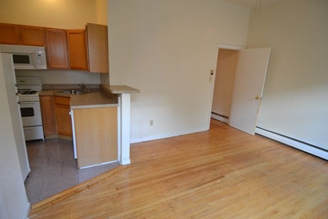 an empty kitchen with wood flooring and a refrigerator